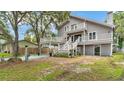 A quaint backyard featuring green grass, paver accents, mature trees and a two-story home at 9934 Peninsular Dr, Gibsonton, FL 33534