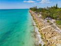 Aerial view of shoreline with turquoise water and rock barrier at 3999 Casey Key Rd, Nokomis, FL 34275