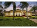 House exterior with palm trees and manicured lawn at dusk at 12209 Cotorro Ave, North Port, FL 34287