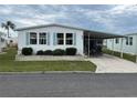 Mobile home with covered carport, landscaping, and screened porch at 626 Cervina Dr, Venice, FL 34285