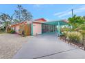 Pink bungalow with covered patio, carport, and tropical landscaping at 7037 Duke St, Englewood, FL 34224
