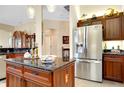 Kitchen island with stainless steel fridge and granite countertop offers sleek design and functionality at 11065 Barnsley Dr, Venice, FL 34293