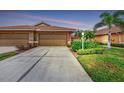 Two-car garage with manicured lawn and landscaping at 218 Auburn Woods Cir, Venice, FL 34292