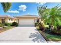 Exterior of a single-story home with a two-car garage, landscaping, and a paved driveway at 194 Padova Way # 32, Nokomis, FL 34275