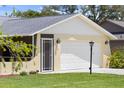 Close up exterior view of the two-car garage and covered porch of the home with green lawn at 566 Viridian St, Englewood, FL 34223