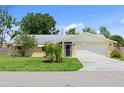 A charming single-story home featuring a well-manicured lawn, a two-car garage, and a beautifully landscaped yard with a weeping willow at 566 Viridian St, Englewood, FL 34223