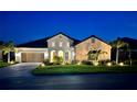 Stunning nighttime view of this stucco home showcasing landscape lighting, lush lawn, and a two-car garage at 284 Bocelli Dr., Nokomis, FL 34275