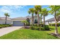 One-story house with gray garage door and tropical landscaping at 15177 Spanish Point Dr, Port Charlotte, FL 33981