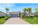 Single-story home with gray garage door, paver driveway, and lush landscaping at 15177 Spanish Point Dr, Port Charlotte, FL 33981