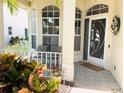 Inviting front porch features decorative columns, seating, and a charming door with intricate wrought iron detail at 334 Melrose Ct, Venice, FL 34292