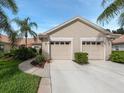 Tan two-car garage with lush landscaping at 688 Back Nine Dr, Venice, FL 34285