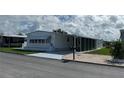 Front view of a white manufactured home with a carport and landscaping at 923 Cortina Blvd, Venice, FL 34285