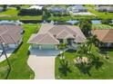 Aerial view of a well-maintained home with an attached two car garage, lush landscaping, and waterfront access at 233 Fairway Rd, Rotonda West, FL 33947