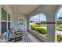 Relaxing front porch with glass-top table, cushioned seating, and lush potted plants at 8509 La Boca Ave, North Port, FL 34287
