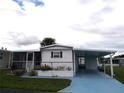 Front view of a white manufactured home with carport and landscaping at 427 Boxwood Dr, Venice, FL 34285