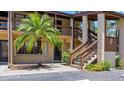 Condo building exterior featuring a palm tree and wooden stairs to the second floor at 8 Quails Run Blvd # 6, Englewood, FL 34223