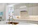 White kitchen with marble countertops, gold fixtures, and a unique backsplash at 1040 Gulf Winds Way, Nokomis, FL 34275