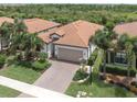 Aerial view of single-Gathering home with tile roof, driveway, and lush landscaping at 10079 Crooked Creek Dr, Venice, FL 34293