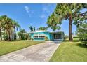 Quaint teal manufactured home nestled on a grassy lot with palm trees at 3364 Goldfinch Ln, Englewood, FL 34224