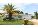 Cute light blue single-story home with a large palm tree in the front yard at 221 Malvern Dr, Venice, FL 34293