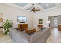 Bright living room featuring coffered ceilings, a ceiling fan, a gray sectional sofa, and tile flooring at 7801 Grande Shores Dr, Sarasota, FL 34240