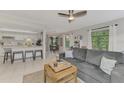 Open concept living room featuring a gray sofa, tile floors, and eat-in kitchen at 5103 Greencroft Rd, Sarasota, FL 34235