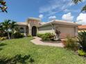 Tan house with lush landscaping, a two-car garage, and walkway at 117 Savona Way, North Venice, FL 34275