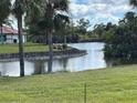 Landscaped backyard featuring a waterfront view, palm trees, and serene natural scenery at 1929 Tradewinds Cir, Venice, FL 34293