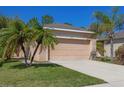 Tan single story house with a two-car garage and lush landscaping at 11954 Tempest Harbor Loop, Venice, FL 34292