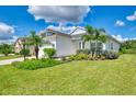 A light-colored house with palm trees, lush landscaping, and a well-manicured lawn at 1640 Still River Dr, Venice, FL 34293