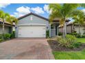 Single-story house with a white garage door, grey exterior, and landscaping at 240 Teramo Way, Nokomis, FL 34275