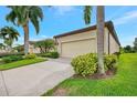 Side view of a tan house with a two-car garage and lush landscaping at 1780 Batello Dr, Venice, FL 34292