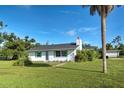 White house with green accents and large yard at 8430 Roosevelt St, Englewood, FL 34224