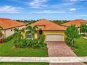 Charming home featuring a paver driveway, lush landscaping, and a well-maintained lawn at 25134 Spartina Dr, Venice, FL 34293