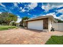 White garage door with stone facade and landscaping at 5280 E Sunnydale Cir, Sarasota, FL 34233