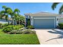 Curb appeal! This light blue house boasts a 2-car garage and lush landscaping at 12273 Stuart Dr, Venice, FL 34293