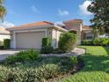 Tan house with tile roof, landscaped yard, and walkway at 126 Cipriani Way, North Venice, FL 34275