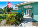 Front view of teal house with porch and landscaping at 2480 Alamander Ave, Englewood, FL 34223