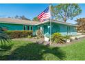 Charming teal house with a well-manicured lawn and American flag at 2480 Alamander Ave, Englewood, FL 34223