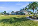 Side view of house with white exterior, green lawn and palm trees at 1507 N Knollwood Dr, Bradenton, FL 34208