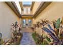 Inviting entrance showcasing a brick walkway, lovely tropical plants, and a pair of double glass doors at 20190 Ragazza Cir # 202, Venice, FL 34293