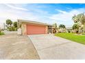 Single-story home with coral garage door and landscaped yard at 3248 Hercules Rd, Venice, FL 34293