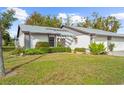 Condo exterior with gray roof, white garage door, and lush landscaping at 605 Apple Ln, Englewood, FL 34223