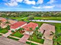 Community view showcasing houses with red tile roofs near a golf course and lake at 5633 Whispering Oaks Dr, North Port, FL 34287