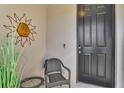 Inviting entryway with black door, wicker chair, and sun-shaped wall art at 5860 Ocean Isle Dr, Nokomis, FL 34275