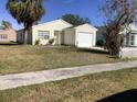 Front yard view of a yellow house with a palm tree and grassy lawn at 20044 Sancraft Ave, Port Charlotte, FL 33954