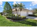 Side view of a villa showcasing its beige exterior, two-car garage, and well-maintained landscaping at 3897 Fairway Dr, North Port, FL 34287