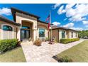 Inviting front entrance with a paved walkway, lush landscaping, and an American flag at 8939 E River Rd, Venice, FL 34293