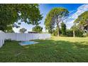 Spacious backyard with a grassy lawn, white fence, and patio furniture at 1605 Phillip Pl, Englewood, FL 34223