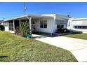 White mobile home with carport, golf cart, and green lawn at 218 Trailorama Dr, North Port, FL 34287